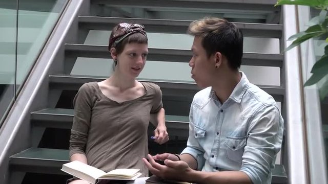 Two students discussing something, while sitting on a staircase