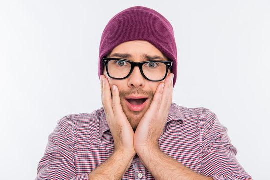 Surprised man in hat and glasses touching his face