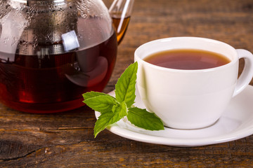 Teacup with teapot on wooden table