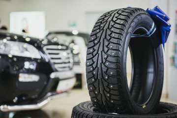 Stack of car tires in the showroom. New cars in bokeh