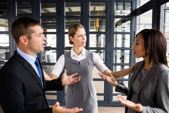 Businesswoman calming down colleagues arguing