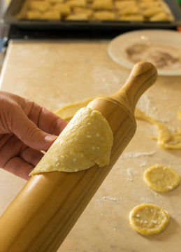Hand with rolling-pin, dough for cookies on the kitchen table