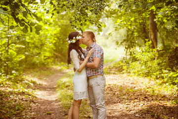 Beautiful girl with flowers circlet is kissing young boyfriend