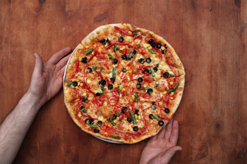 Pizza Vegetariana on wooden table with man hands. Italian cuisine fast food, top view.