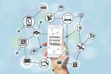 Internet of everything concept with male hand holding modern smart phone in front of light blue...