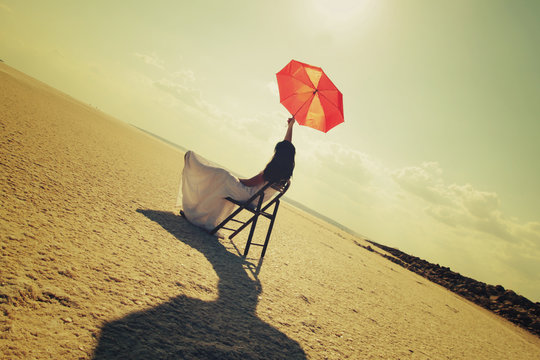 çölde tek başına beyaz elbiseli bir kadın kırmızı şemsiye tutuyor,  sandalyede oturan huzurlu kadın doğayla iç içe güneş ve gün konsantrasyon  ve huzur ile neşeli yaşam ve yeni bir hayat Stock Photo | Adobe Stock