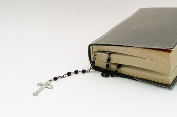rosary beads in bible book on white background