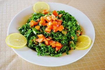 Plate of parsley taboule (tabbouli) salad with lemons