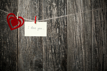 Handwritten words I love you and hearts on wooden background.