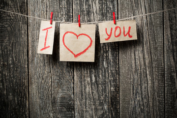 Handwritten words I love you and hearts on wooden background.