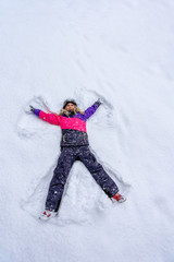 Fototapeta na wymiar Top view of cute girl lying on snow