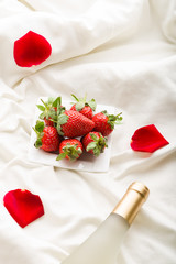 Strawberry, wine and  rose petals on bed - 100580998