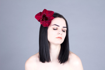 Naklejka premium Beautiful woman with closed eyes and a red flower in her hair