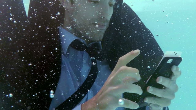 Businessman using smartphone underwater