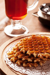 Belgian waffles on wooden table with glass of tea