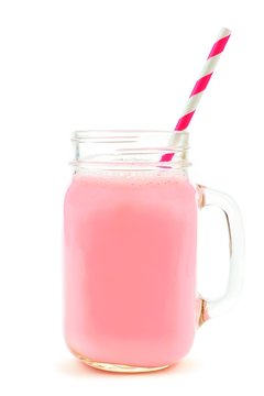 Strawberry milk in a glass mason jar mug with striped paper straw isolated on a white background