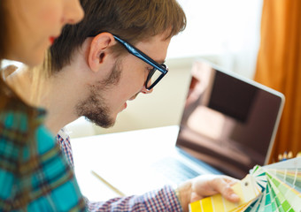 Young colleague - manand woman looking to a color paint palette