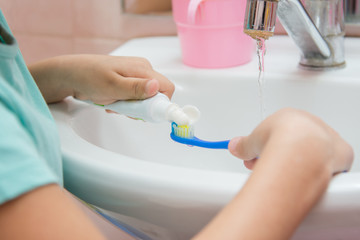 The child squeezes the toothpaste from a tube on toothbrush
