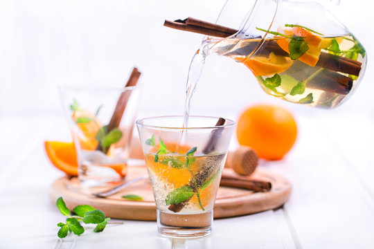 Tea with orange, mint and cinnamon on wooden white background - Powered by Adobe