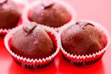 Chocolate Truffles on red surface with focus on foreground