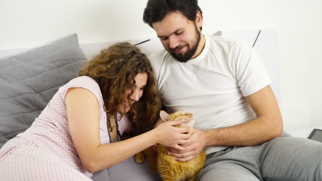 couple in bed caressing a ginger cat slow motion