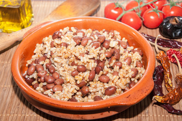 Cazuela de arroz con alubias y varios ingredientes sobre un mantel de rafia