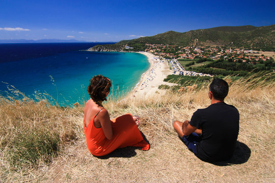 A couple sitting and enyoing the view of the Solanas Beach in Sardinia.