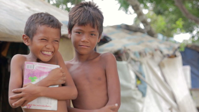 Cambodian boys in slum, shacks at background 