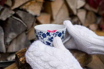 Cup of tea or coffee  with trace of red lipstick in white mitten