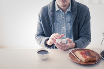 朝食を食べながらスマートフォンを操作している日本人男性