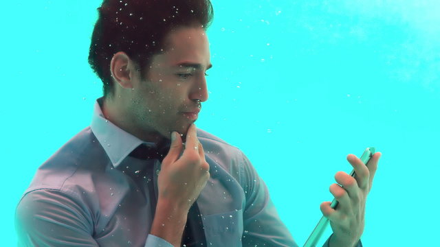 Thoughtful man using smartphone underwater 