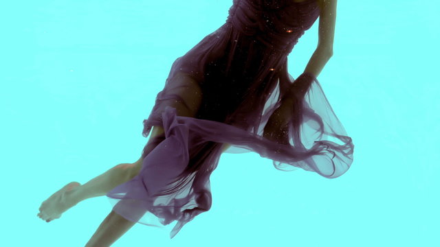 Woman with maxi dress swimming underwater 