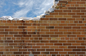 crumbling brick wall with wispy white clouds in blue sky