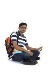 indian young male student surfing while sitting on the floor