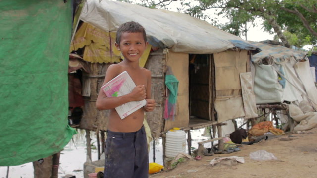 Boy in slum holding book want to go school