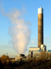Fototapeta na wymiar Smoke from factory with big chimney against blue sky