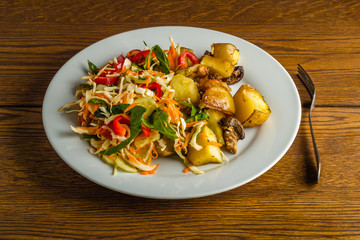 Fried potato and fresh salad on the plate 