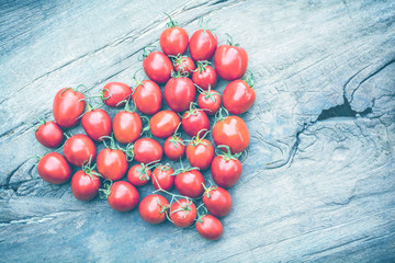 shape heart of tomatoes on old wooden table background, vintage color
