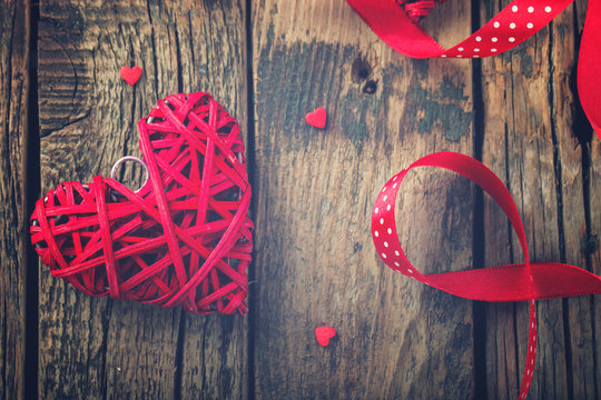 Heart decorated with a red ribbon for a romantic Valentine's day celebration, on vintage wooden background.Toned image.Vintage style.selective focus.