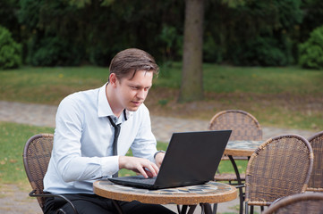 young excited businessman working on laptop outdoors