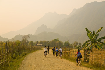 Children cycling, Sunset at limestone mountains of Vang Vieng, Laos - obrazy, fototapety, plakaty