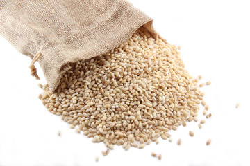 Burlap sack with pearl barley spilling out over a white background