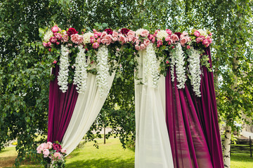 wedding arch with flowers situated in forest. Wedding ceremony i
