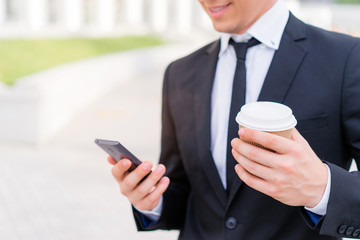 businessman using smartphone and holding cup