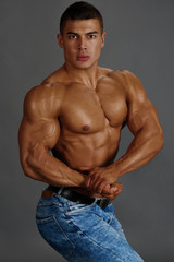 Fototapeta na wymiar Muscular man in jeans posing, showing biceps.