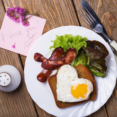 Scrambled eggs with heart shaped sausage for breakfast