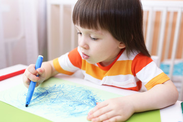 Cute little 3 years boy paints with felt pens