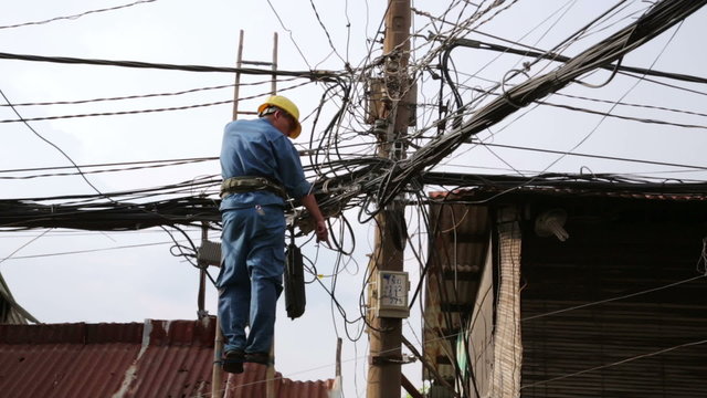 electrician fixing, repairing messy electric cables in hanoi slums, vietnam