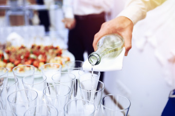 Waiter pours white wine in wineglass