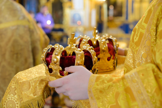 Crown crowned in the hands of the priest. Greek Orthodox Weddings in the Christian Church. Spiritual priest is crowned newlyweds with Golden crowns. Tradition of marriage in the Christian religion.